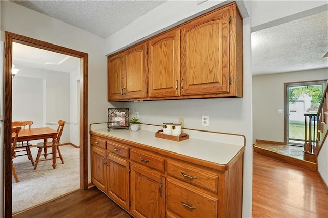 8025 Woodstone St, Lenexa, KS 66219 - kitchen featuring a textured ceiling, dark wood-type flooring, light countertops, and brown cabinets