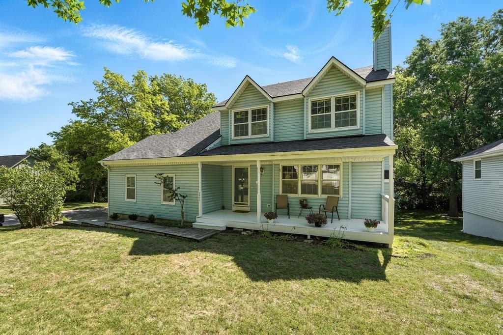 8025 Woodstone St, Lenexa, KS 66219 - view of front facade with a chimney, a front lawn, and covered porch