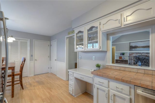 15005 W 94th St, Lenexa, KS 66215 - kitchen featuring stainless steel dishwasher, light wood finished floors, glass insert cabinets, tile counters, and white cabinets
