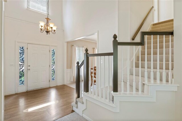 7642 N Atkins Pl, Kansas City, MO 64152 - entrance foyer with stairs, a chandelier, wood finished floors, and a towering ceiling