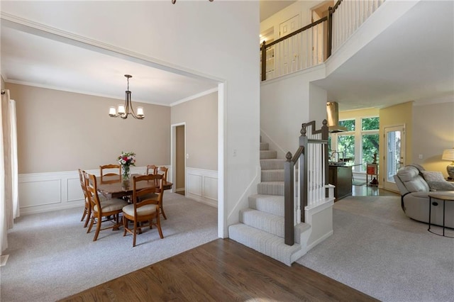 7642 N Atkins Pl, Kansas City, MO 64152 - dining area featuring stairs, ornamental molding, dark wood finished floors, a chandelier, and dark colored carpet