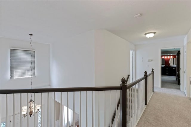 7642 N Atkins Pl, Kansas City, MO 64152 - hallway featuring a chandelier, light colored carpet, and an upstairs landing