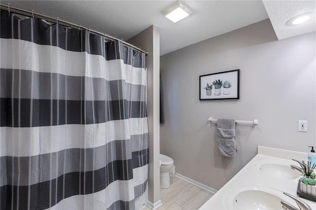 7642 N Atkins Pl, Kansas City, MO 64152 - bathroom with double vanity, a textured ceiling, a shower with curtain, and wood finished floors