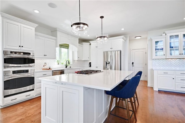 16821 Goddard St, Overland Park, KS 66221 - kitchen featuring stainless steel appliances, decorative backsplash, white cabinets, a kitchen island, and a kitchen bar