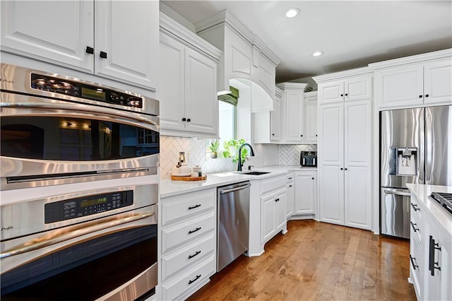 16821 Goddard St, Overland Park, KS 66221 - kitchen with stainless steel appliances, white cabinets, recessed lighting, light wood-style floors, and decorative backsplash