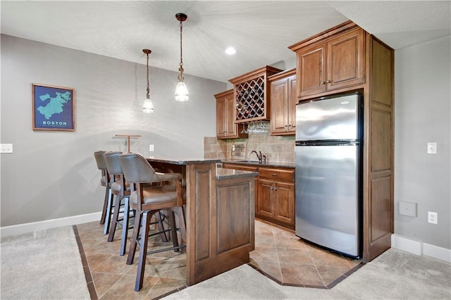 16821 Goddard St, Overland Park, KS 66221 - kitchen featuring freestanding refrigerator, a kitchen bar, a sink, brown cabinetry, and recessed lighting