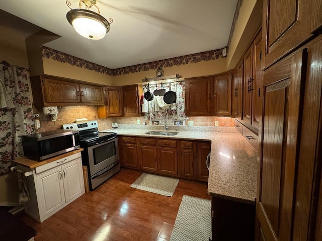 308 E Arrow St, Marshall, MO 65340 - kitchen featuring stainless steel appliances, a sink, tasteful backsplash, wood finished floors, and light countertops