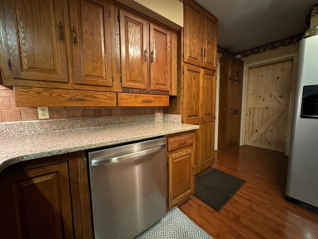 308 E Arrow St, Marshall, MO 65340 - kitchen featuring appliances with stainless steel finishes, wood finished floors, brown cabinets, decorative backsplash, and light countertops