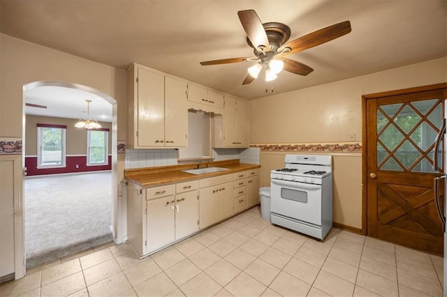 6608 N Edison Ave, Kansas City, MO 64151 - kitchen with gas range gas stove, a sink, arched walkways, ceiling fan, and white cabinets