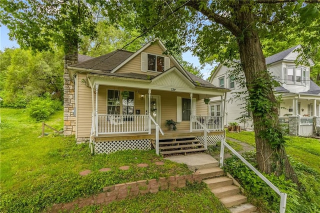 124 Wildwood St, Excelsior Springs, MO 64024 - bungalow-style home with covered porch, a chimney, a front yard, and roof with shingles