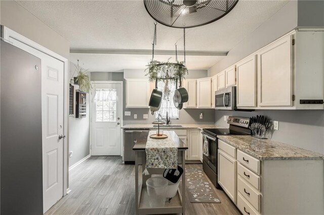 124 Wildwood St, Excelsior Springs, MO 64024 - kitchen featuring appliances with stainless steel finishes, light wood-type flooring, a sink, light stone countertops, and baseboards
