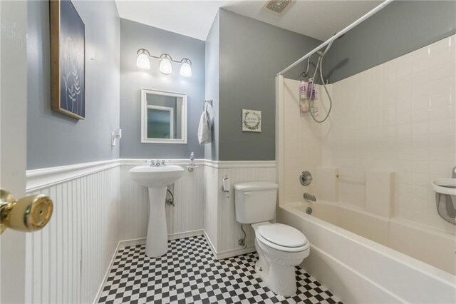 124 Wildwood St, Excelsior Springs, MO 64024 - full bathroom featuring toilet, tile patterned floors, wainscoting, tub / shower combination, and a sink