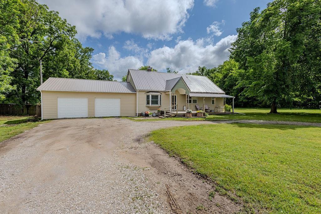 3005 W W 8th St, Coffeyville, KS 67337 - view of front facade with a porch, an attached garage, metal roof, and driveway