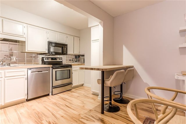 3606 Gillham Rd Unit 25, Kansas City, MO 64111 - kitchen featuring appliances with stainless steel finishes, tasteful backsplash, white cabinets, and light countertops