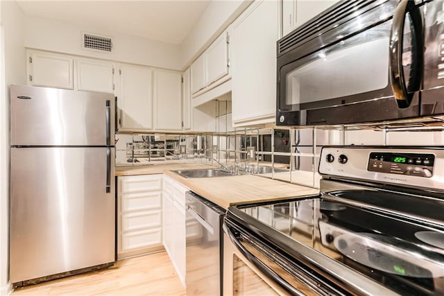 3606 Gillham Rd Unit 25, Kansas City, MO 64111 - kitchen with stainless steel appliances, white cabinets, light countertops, light wood finished floors, and decorative backsplash