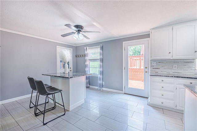 2200 E 126th St, Kansas City, MO 64146 - kitchen featuring white cabinets, dark stone countertops, tasteful backsplash, a breakfast bar, and a textured ceiling