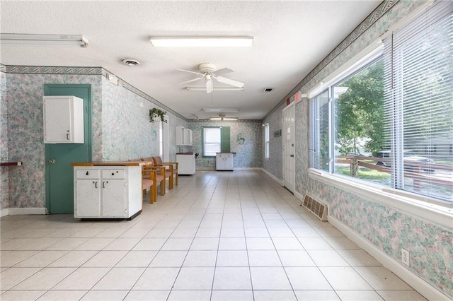 7001 Hunter St, Raytown, MO 64133 - kitchen with wallpapered walls, ceiling fan, white cabinets, a textured ceiling, and baseboards