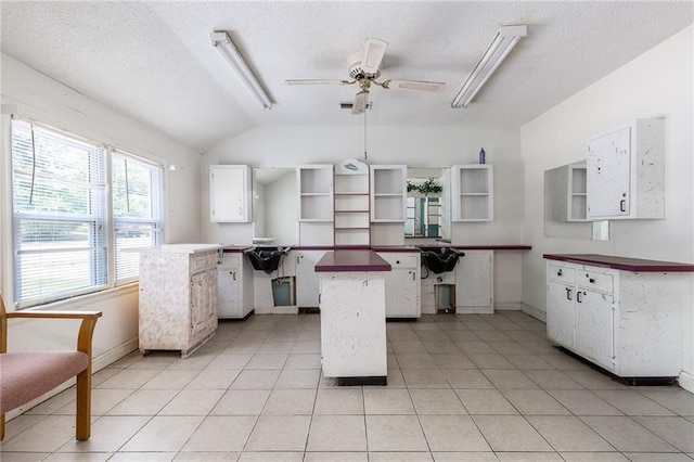 7001 Hunter St, Raytown, MO 64133 - kitchen with open shelves, vaulted ceiling, baseboards, white cabinetry, and a textured ceiling