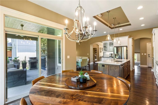 11446 S Longview Rd, Olathe, KS 66061 - dining area featuring arched walkways, a tray ceiling, dark wood-style flooring, a chandelier, and recessed lighting