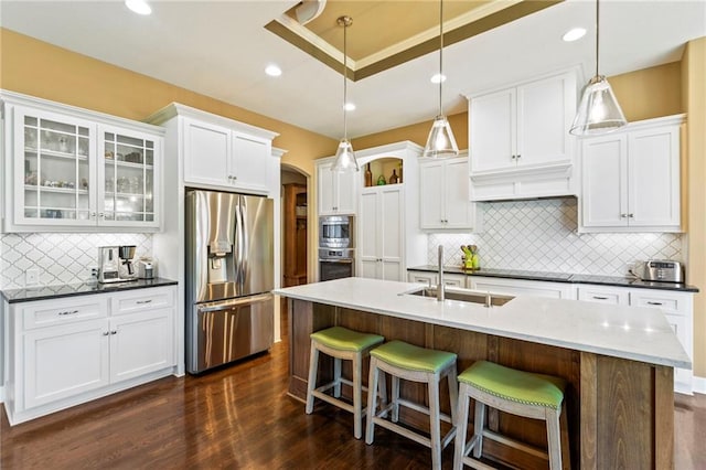 11446 S Longview Rd, Olathe, KS 66061 - kitchen featuring appliances with stainless steel finishes, arched walkways, decorative backsplash, a kitchen breakfast bar, and glass insert cabinets