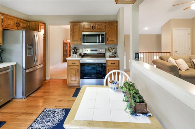 156 SE 1181st Rd, Knob Noster, MO 65336 - kitchen with stainless steel appliances, light wood finished floors, brown cabinets, a ceiling fan, and open floor plan