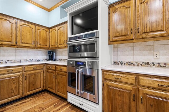13008 Fontana St, Leawood, KS 66209 - kitchen featuring stainless steel double oven, brown cabinets, tasteful backsplash, and ornamental molding