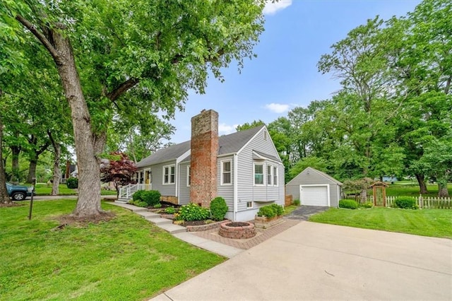 5741 Hadley St, Merriam, KS 66202 - view of front of property with an outdoor structure, a detached garage, a chimney, concrete driveway, and a front yard