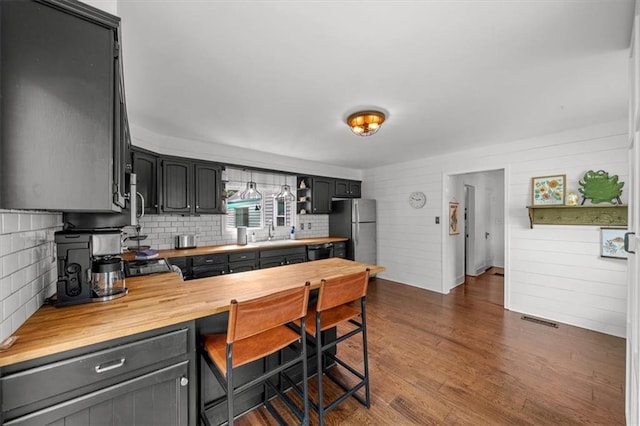 5741 Hadley St, Merriam, KS 66202 - kitchen featuring freestanding refrigerator, wooden counters, a sink, decorative backsplash, and dark wood-style flooring