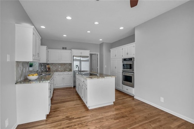 12428 Cambridge Cir, Leawood, KS 66209 - kitchen featuring a sink, stainless steel appliances, light stone counters, white cabinets, and a center island