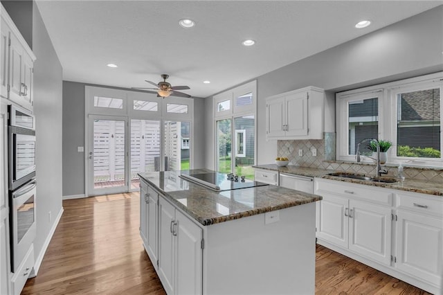 12428 Cambridge Cir, Leawood, KS 66209 - kitchen featuring a sink, appliances with stainless steel finishes, a center island, ceiling fan, and decorative backsplash