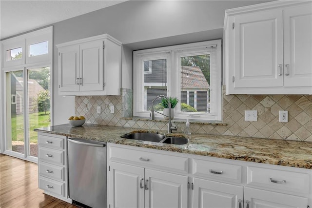 12428 Cambridge Cir, Leawood, KS 66209 - kitchen with stainless steel dishwasher, a sink, white cabinetry, and light stone countertops