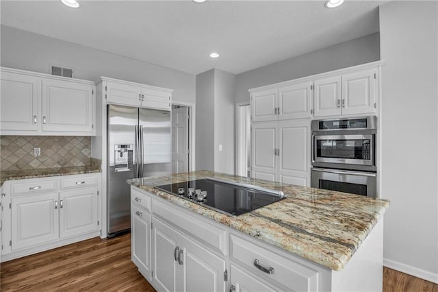 12428 Cambridge Cir, Leawood, KS 66209 - kitchen featuring appliances with stainless steel finishes, light stone counters, dark wood-type flooring, white cabinets, and decorative backsplash