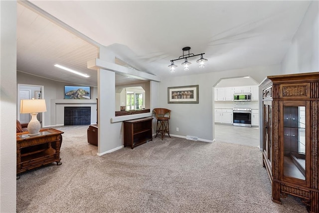 3906 Oo Hwy, Odessa, MO 64076 - living room with a fireplace, light colored carpet, track lighting, baseboards, and vaulted ceiling