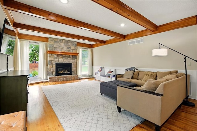 12844 Granada Ln, Leawood, KS 66209 - living area featuring beam ceiling, wood finished floors, a stone fireplace, and a wainscoted wall