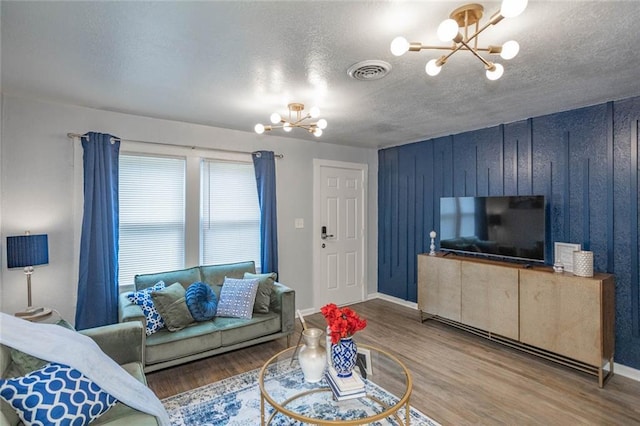 3802 Roanoke Rd, Kansas City, MO 64111 - living room featuring a chandelier, wood finished floors, a textured ceiling, baseboards, and wood walls