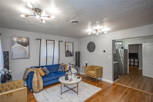 3802 Roanoke Rd, Kansas City, MO 64111 - living room with a chandelier, wood finished floors, a textured ceiling, and baseboards