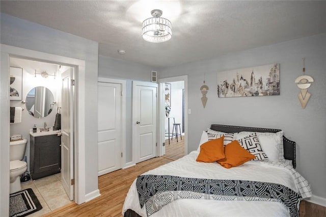 3802 Roanoke Rd, Kansas City, MO 64111 - bedroom with a sink, light wood-style floors, baseboards, and ensuite bath