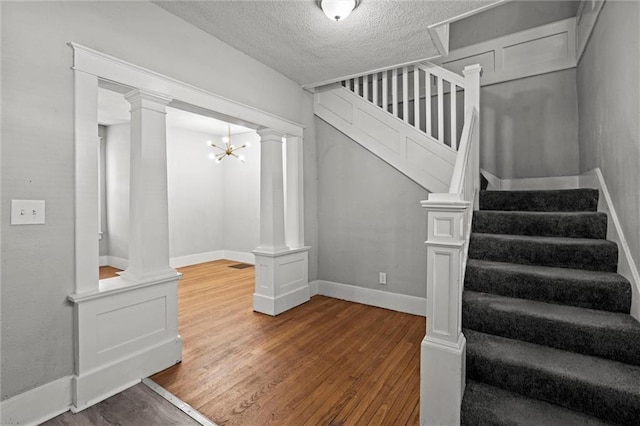 509 Pottawatomie St, Leavenworth, KS 66048 - staircase with wood finished floors, decorative columns, and a textured ceiling