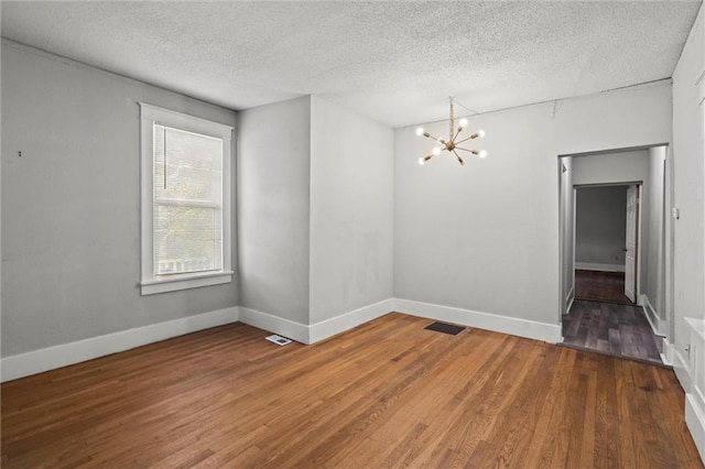 509 Pottawatomie St, Leavenworth, KS 66048 - empty room featuring a chandelier, wood finished floors, and a textured ceiling