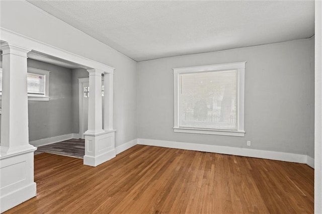 509 Pottawatomie St, Leavenworth, KS 66048 - unfurnished room featuring ornate columns, wood finished floors, and a textured ceiling