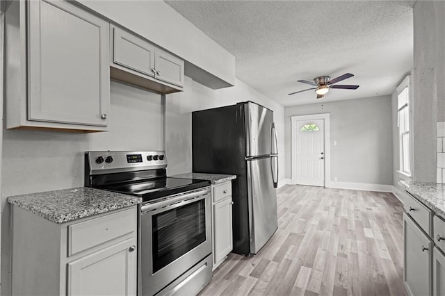 509 Pottawatomie St, Leavenworth, KS 66048 - kitchen featuring stainless steel appliances, a ceiling fan, a textured ceiling, light wood-style flooring, and light stone counters