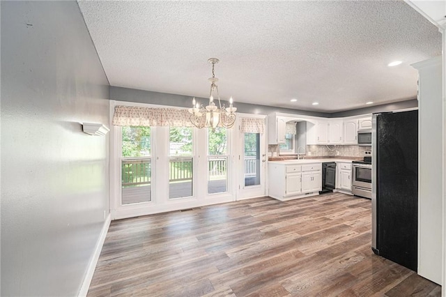 212 Hampton Dr, Smithville, MO 64089 - kitchen featuring stainless steel appliances, a textured ceiling, light countertops, a chandelier, and light wood-style floors