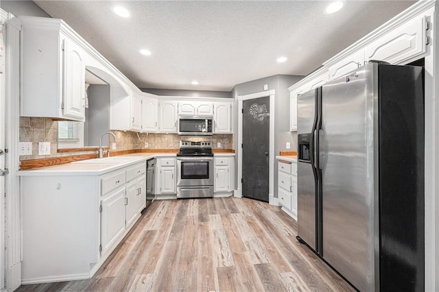 212 Hampton Dr, Smithville, MO 64089 - kitchen with appliances with stainless steel finishes, light wood-style flooring, recessed lighting, light countertops, and tasteful backsplash