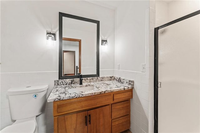 804 5th St, Baldwin City, KS 66006 - full bathroom featuring tile walls, vanity, toilet, a shower stall, and a wainscoted wall