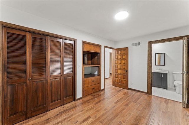 804 5th St, Baldwin City, KS 66006 - unfurnished bedroom with a closet, light wood-style floors, baseboards, a sink, and connected bathroom
