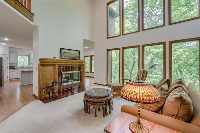 5317 NW Bluff Way, Parkville, MO 64152 - living area featuring a towering ceiling, a tiled fireplace, and light wood finished floors