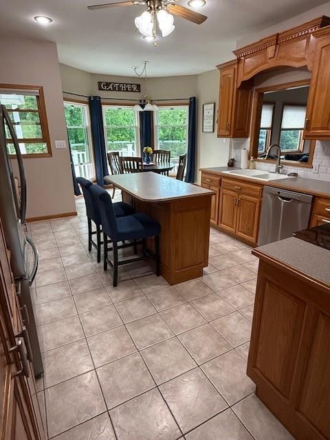 5604 Pleasant Ave, Saint Joseph, MO 64503 - kitchen featuring stainless steel dishwasher, ceiling fan, light tile patterned floors, black fridge, and a kitchen island