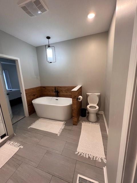 5604 Pleasant Ave, Saint Joseph, MO 64503 - bathroom with a freestanding tub, toilet, and wainscoting