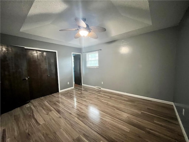 1 N Vine View St, Platte City, MO 64079 - unfurnished bedroom with wood finished floors, baseboards, a tray ceiling, and ceiling fan