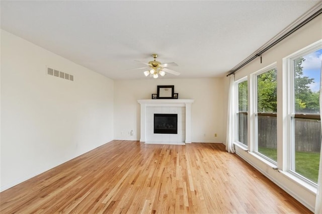 15050 W 145th St, Olathe, KS 66062 - unfurnished living room featuring light wood-type flooring, a ceiling fan, a tiled fireplace, and baseboards